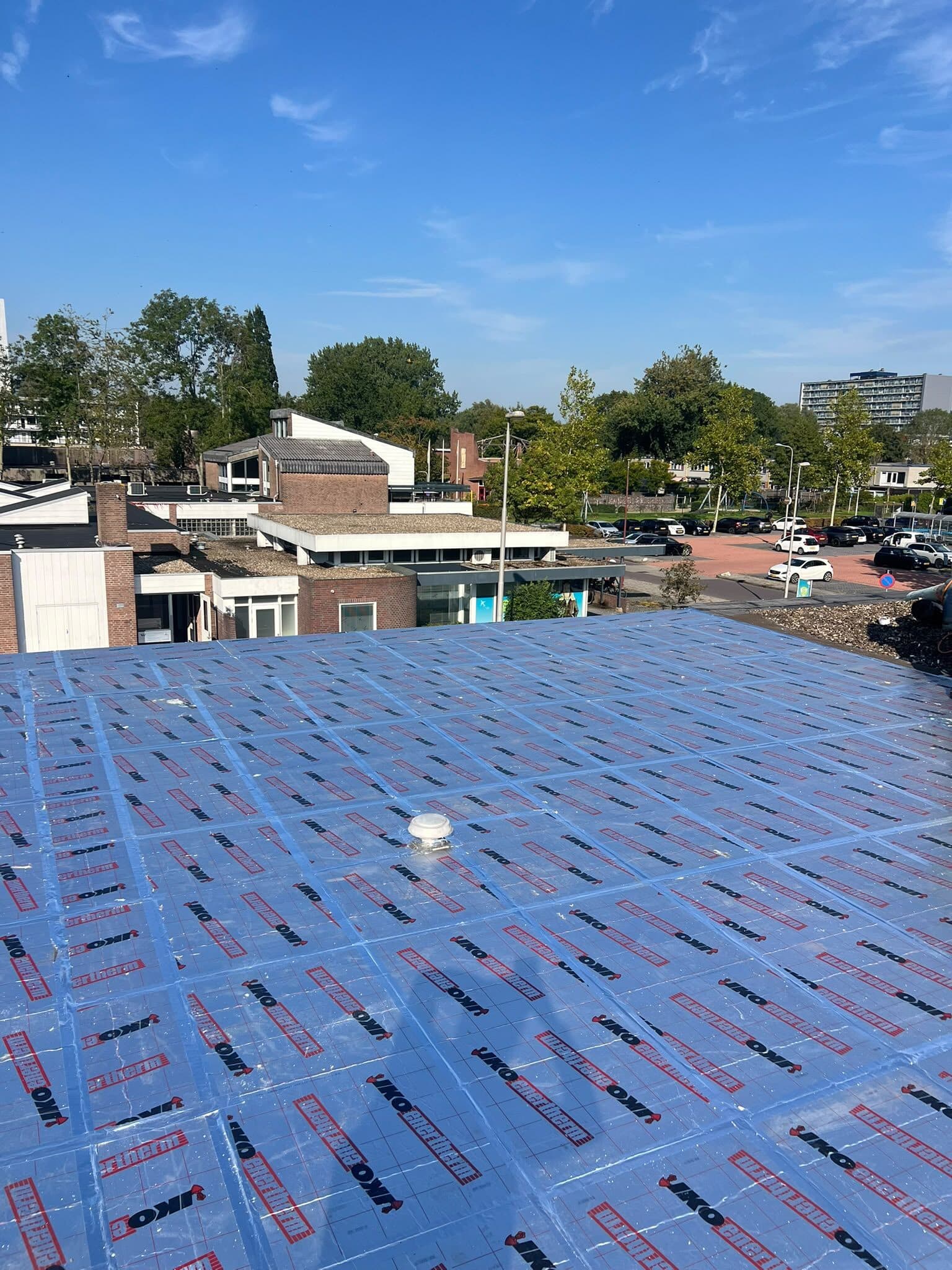 Plat dak volledig belegd met PIR-isolatieplaten onder een blauwe lucht